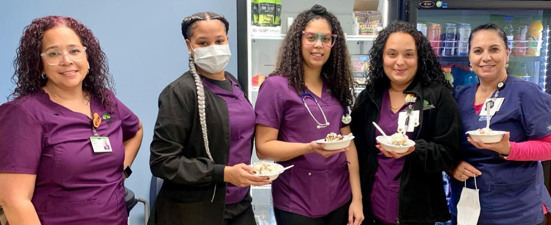 a group of women wearing scrubs and medical masks holding food