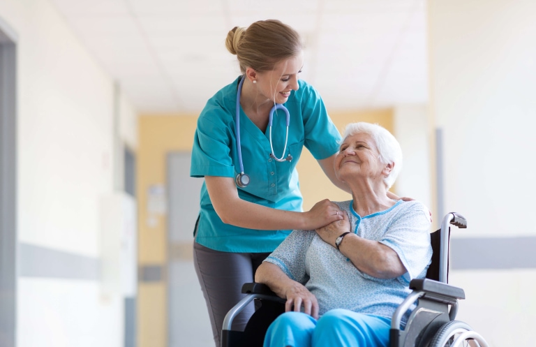 a woman in a wheelchair with a nurse touching her shoulder