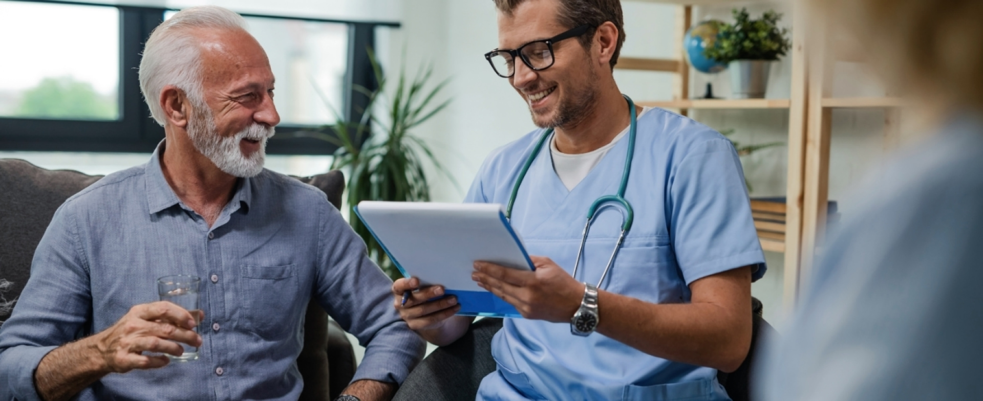 a man in blue scrubs and glasses looking at a tablet