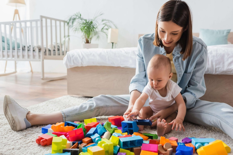 a woman and baby playing with blocks