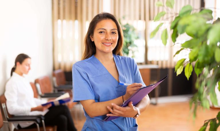 a woman in blue scrubs holding a clipboard